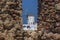 A glimpse through the stone window of Oia Castle towards the windmills of Oia, Santorini