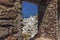 A glimpse through the stone window of Oia Castle towards the windmills and white buildings of Oia, Santorini