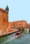 Glimpse of Venice with one of its canals with boats, historic buildings and people walking on sidewalks and bridge, It