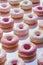 Glistening pink frosted donuts arranged neatly, Ideal for bakery advertising and food blogging. - AI Generated