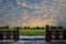 Glisteningly golden sky over green field with wooden balcony