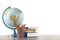 Globe, school supplies and books on wooden table against white background. Geography lesson