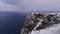 Globe sculpture on snow-covered rock cliff of North Cape (Nordkapp), Norway with few tourists and arctic sea in winter.