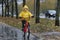 Gloomy boy in a yellow raincoat rides a bicycle along a wet alley in the rain. Autumn day