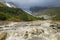 Gloomy dramatic landscape with mountain river Adishi, forest and glacier on a sunny day with clouds