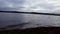 Gloomy lake under overcast sky in summer day. Cloudy skies over murky lakeside landscape view