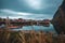 Gloomy sky over the calm lake with red buildings in Norwegen, Lofoten, Fischerdorf Reine