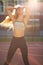 Glorious fitness girl with perfect body and long lush hair posing on a tennis court in rays of sun