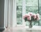 Glorious pastel pink bouquet of peonies in glass jug on floor by window. Flowers in interior design.