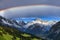 Glorious rainbow in stormy skies over snowy mountains like the Swiss Alps