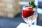 Glossy red strawberry floating in a glass of drinking water