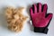 Glove for combing wool and tangles in cats next to a pile of wool.