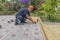 A gloved craftsman lays paving stones in layers. Brick paving slabs for professional use. Laying gray concrete paving slabs in the