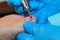 A gloved craftsman removes the nail polish from the toe plate with a milling cutter.