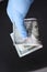 Gloved hand holds hundred dollar bill closeup