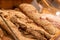 Gloved hand of mature female customer taking fresh bread with sesame sprinkles