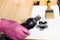 Gloved hand pours wood stain from bottle into jar