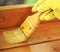 Gloved hand varnishing plank