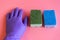 Gloved hand with washcloth on pink background. Rubber gloves and a washcloth for cleaning on a pink background. Set of rubber