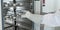 A gloved lab technician removes hot sample bottles from the drying chamber