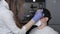 A gloved makeup artist corrects, shapes, and colors the eyebrows of the client in a protective mask at home during the