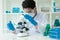 A gloved scientist pours blue acid into a test tube with clear liquid. Scientific research