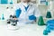 A gloved scientist pours blue acid into a test tube with clear liquid. Scientific research