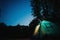 Glowing blue tent in the forest under a starry evening sky.