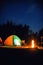 Glowing camping tent near bonfire in wilderness