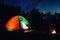 Glowing camping tent near bonfire in wilderness