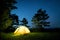 Glowing camping tent in the night mountain forest under a starry sky