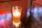 Glowing candle on reflective table with soft pink and orange lights