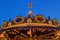 A glowing decoration of carousel on a dark blue sky at dusk.