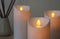 Glowing decorative LED candles on grey background, closeup view