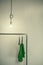 Glowing electric light bulb above the clothes hanger . Green dress on the hanger under light bulbs. Light bulb on the wall backgr