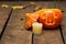 Glowing evil Halloween pumpkin on wooden old floor with dry autumn leaves