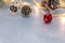 Glowing garland decorated with pine cones and jingle bells on silver desk