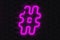 Glowing hashtag symbol of violet color on dark wall. World trends