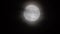 Glowing huge full moon as seen from earth through the clouds against starry night sky. Large full moon moves across the
