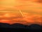 Glowing light trails captured at sunset in an orange sky with a skyline silhouette