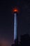 Glowing lighthouse on the background of the starry sky