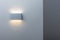 A glowing modern aluminum led lamp on the gray wall. Free space