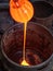 The glowing molten glass drip into the container between the waste material