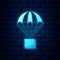 Glowing neon Box flying on parachute icon isolated on brick wall background. Parcel with parachute for shipping