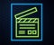 Glowing neon line Movie clapper icon isolated on brick wall background. Film clapper board. Clapperboard sign. Cinema