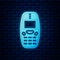 Glowing neon Old vintage keypad mobile phone icon isolated on brick wall background. Retro cellphone device. Vintage 90s