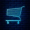 Glowing neon Shopping cart icon isolated on brick wall background. Online buying concept. Delivery service sign