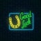 Glowing neon sign with good luck wish and horseshoe in rectangle frame on dark brick wall background.