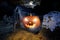 Glowing orange halloween pumpkin with scyry zombie hand on old graveyard front of full moon black raven church dark night spooky