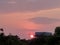 Glowing orange sun beside water head tank in rural area